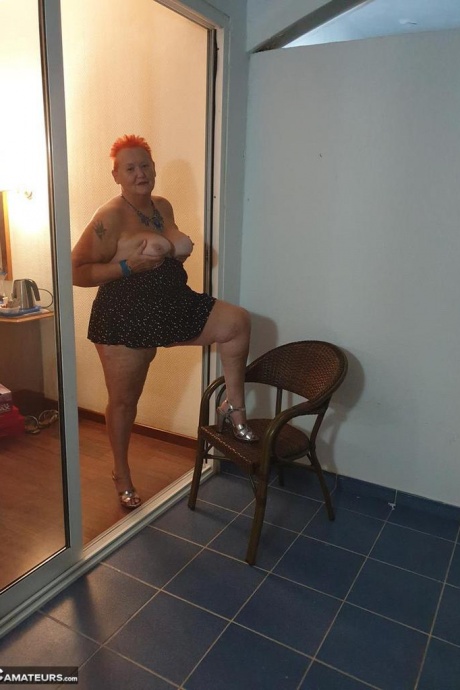 Толстая бабуля с короткими рыжими волосами прижимается своими большими сиськами и задницей к стеклу 19