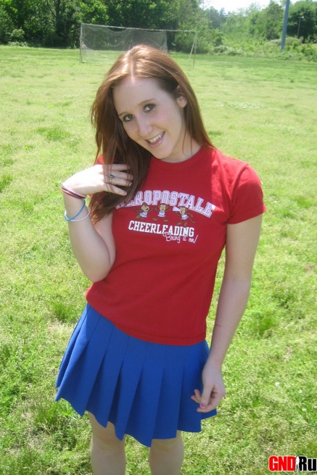 Молодо выглядящая рыжеволосая красотка демонстрирует свои сиськи и нижнее белье на футбольном поле 6