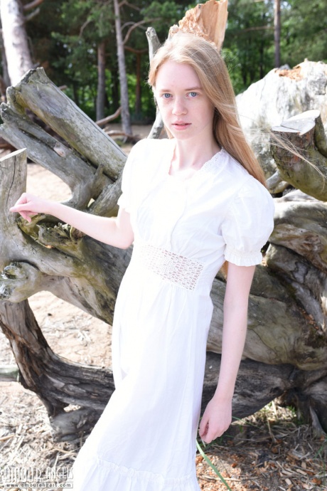 Тощий подросток с рыжими волосами раздевается догола на пляже перед обветренным деревом 1