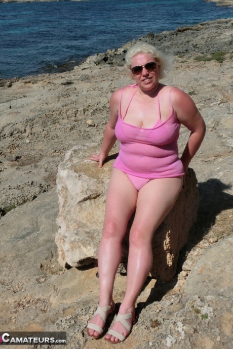 Пухленькая пожилая блондинка Барби раздевается в тени у океана 1