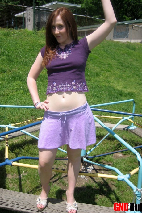 Молодая рыжеволосая красотка демонстрирует свою грудь и трусики на детской площадке 6
