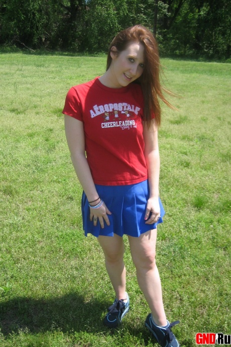 Молодо выглядящая рыжеволосая красотка демонстрирует свои сиськи и нижнее белье на футбольном поле 3