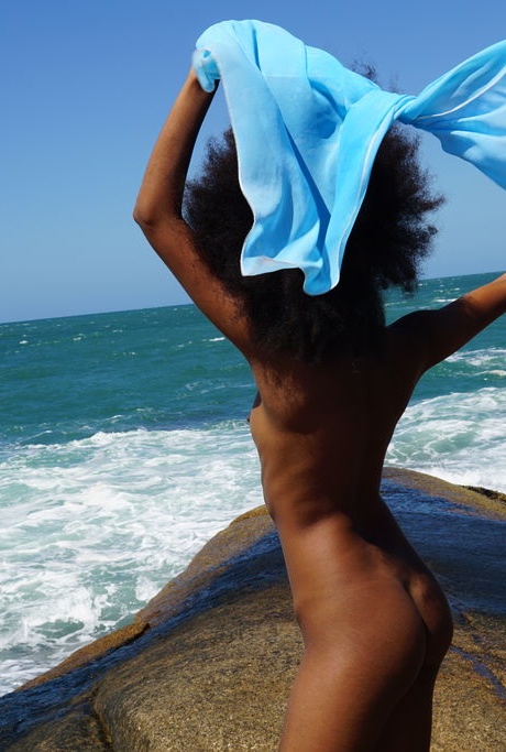 Чернокожая девушка с большой грудью Айседора показывает свою лысую щель и горячую попку на берегу океана 2
