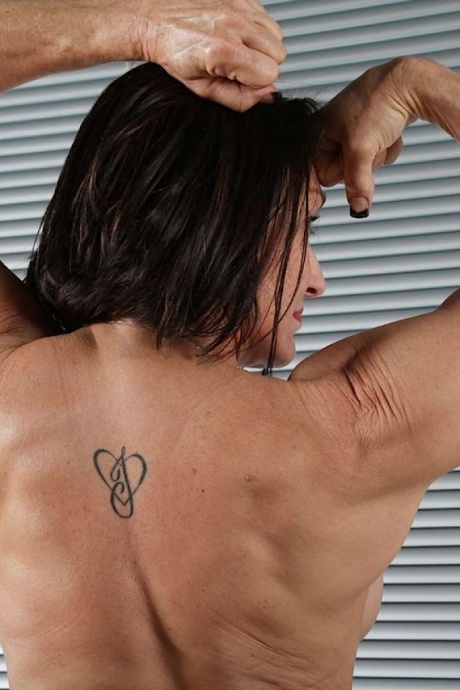 Женщина-культурист сгибается после раздевания на коврике в черных носках 16