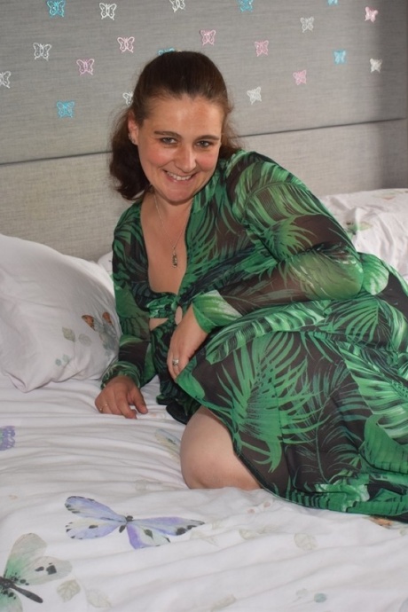 Толстая женщина обнажает себя на кровати в длинном платье 9