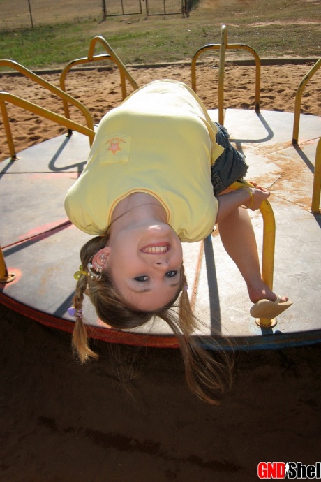 Симпатичная девушка обнажает свой лифчик и трусики под юбкой на детской площадке 8