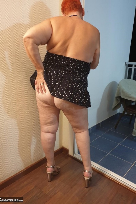 Толстая бабуля с короткими рыжими волосами прижимается своими большими сиськами и задницей к стеклу 3