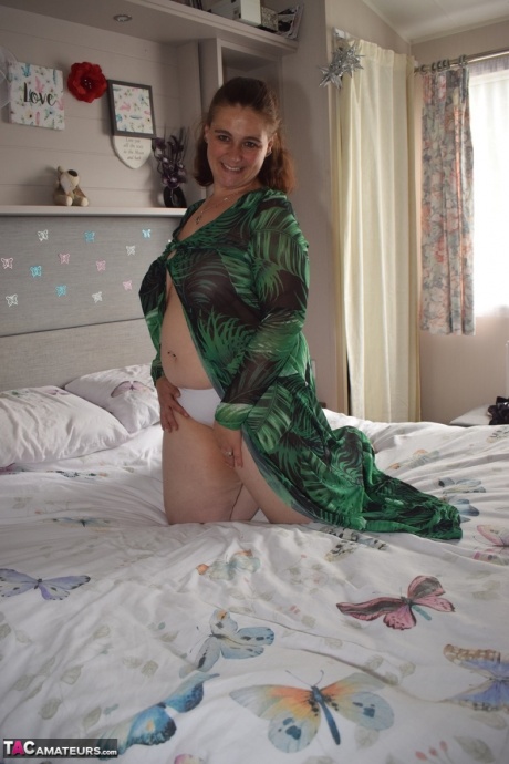 Толстая женщина обнажает себя на кровати в длинном платье 6