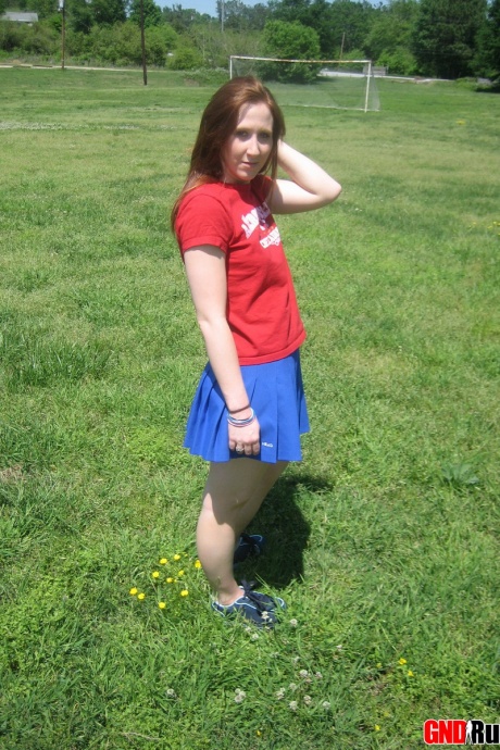 Молодо выглядящая рыжеволосая красотка демонстрирует свои сиськи и нижнее белье на футбольном поле 10