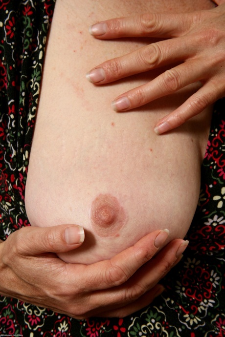 Пожилая женщина обхватывает грудь руками, прежде чем продемонстрировать свой волосатый кустик на диване